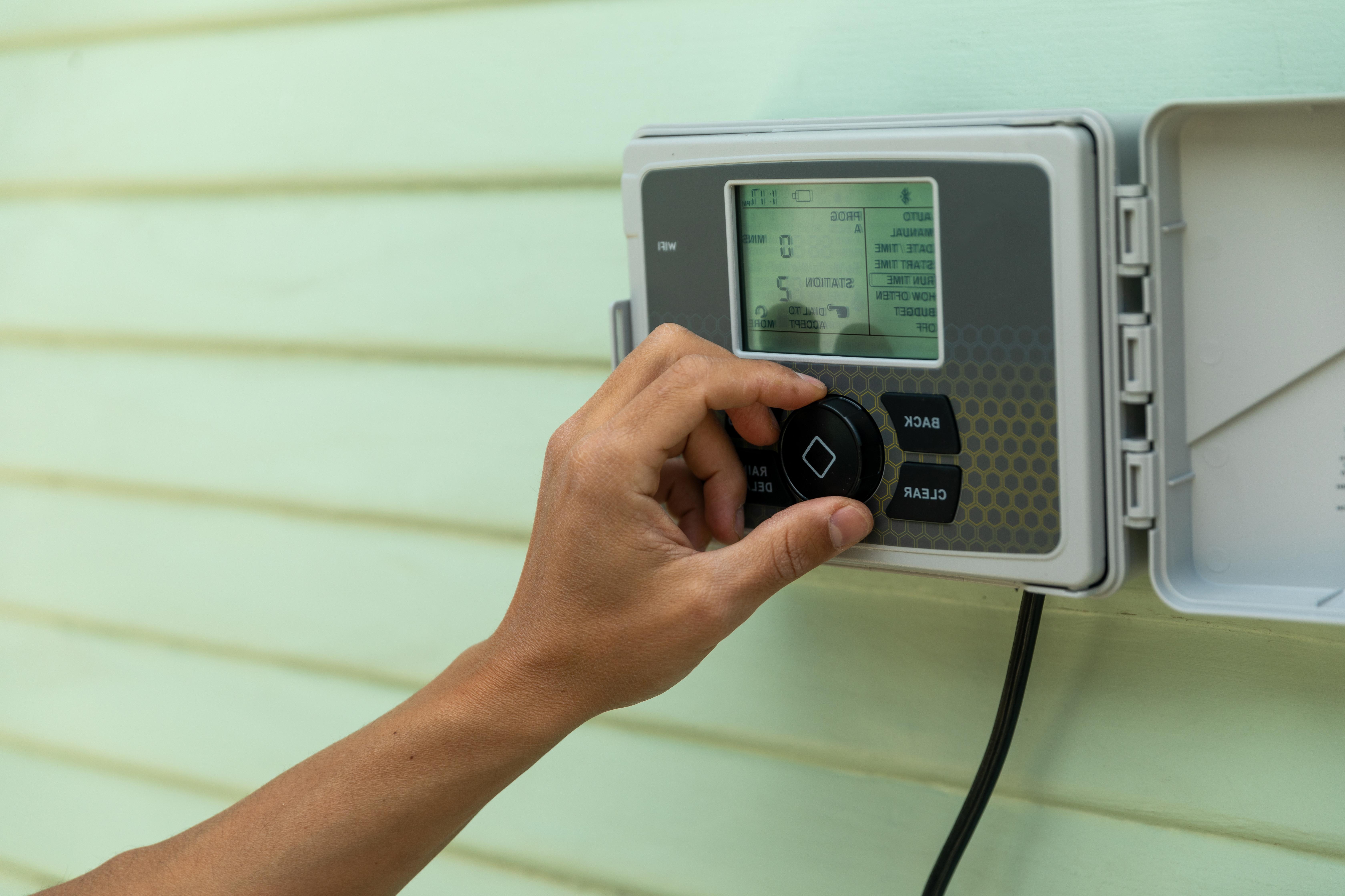 A person adjusts a smart sprinkler controller provided as a part of a water conservation program.